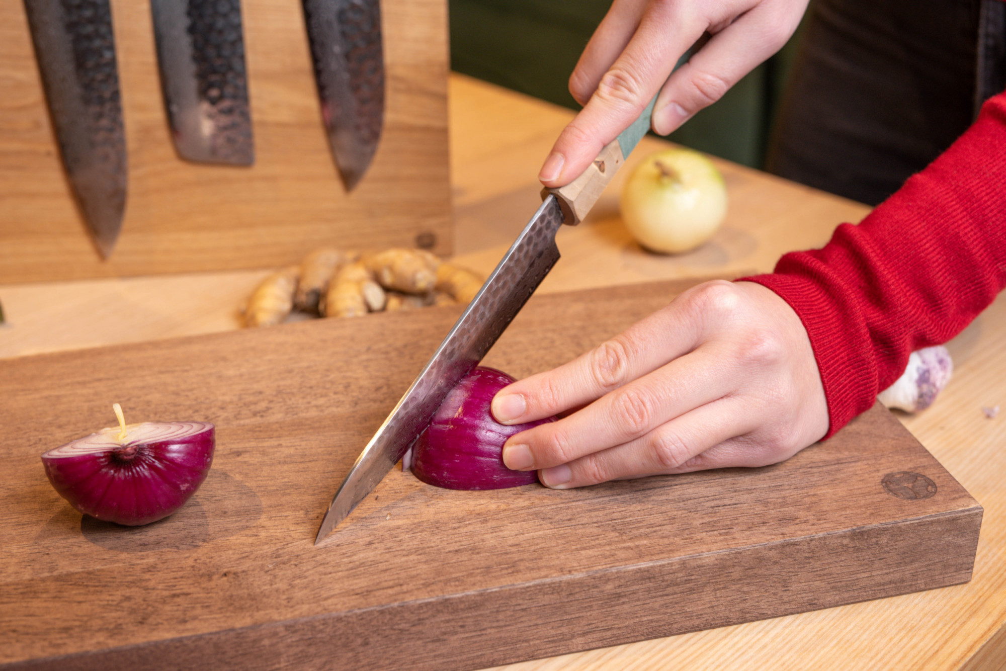 Sakai kyuba santoku blue cutting an onion on walnut cutting board