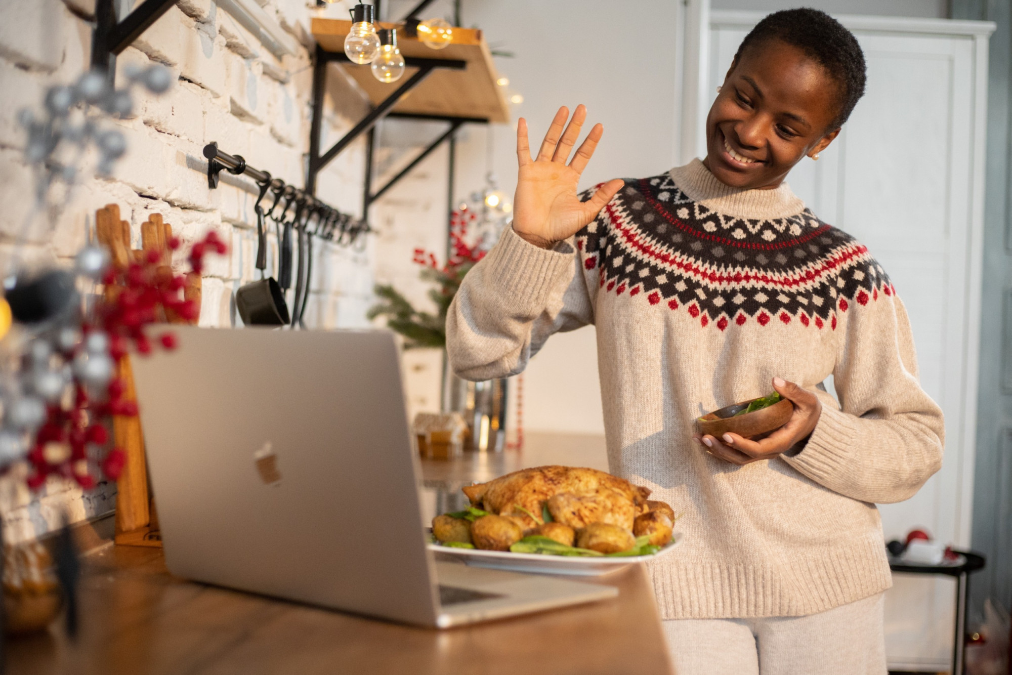 Woman waving at computer with full cook meal