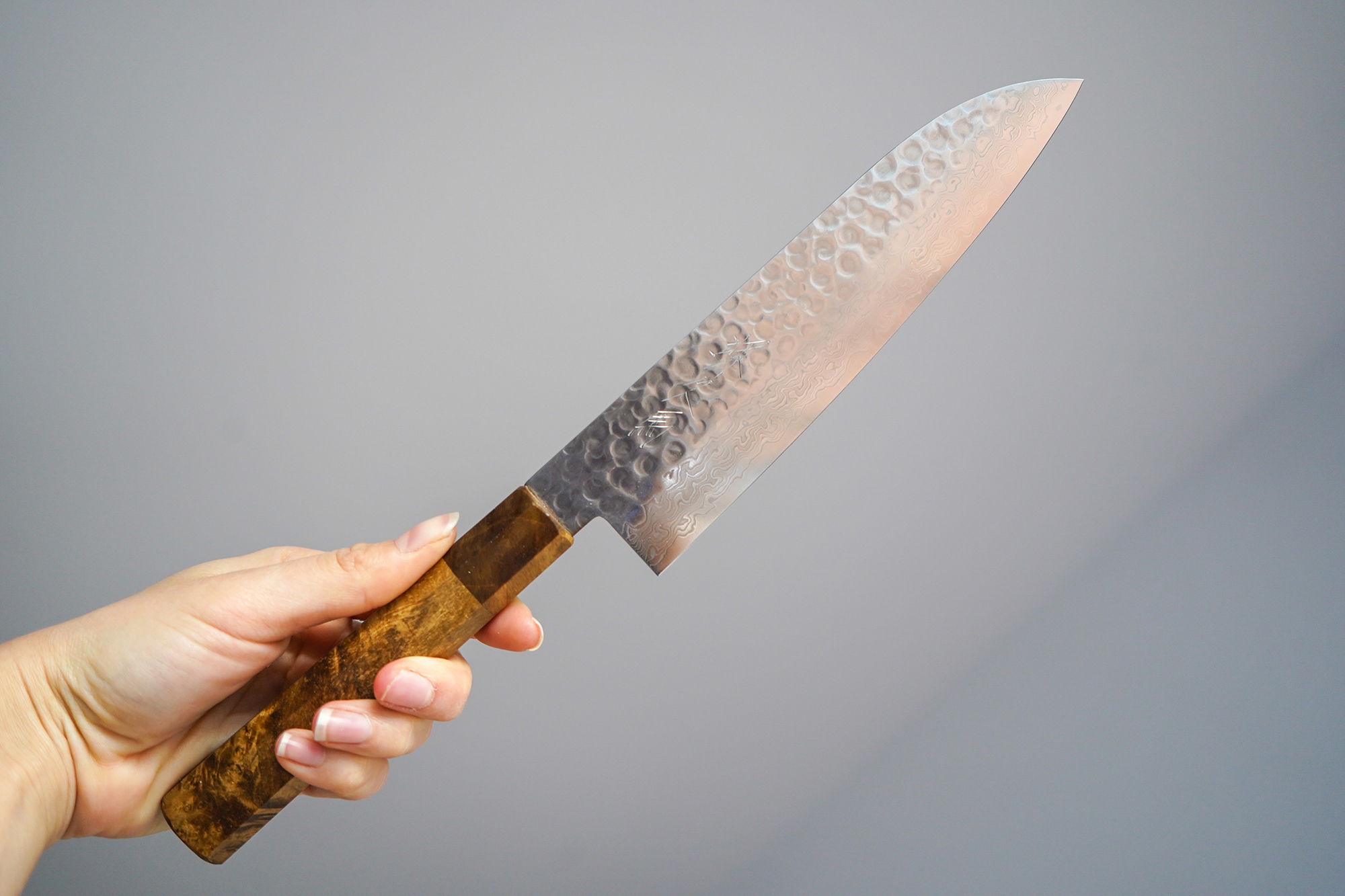 Sakai Kyuba – Chef’s Knife – The Santoku with Natural Brown handle held by woman