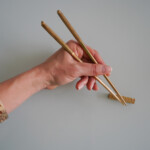 Signature Brass Chopsticks Inc. Rest - in hand white background