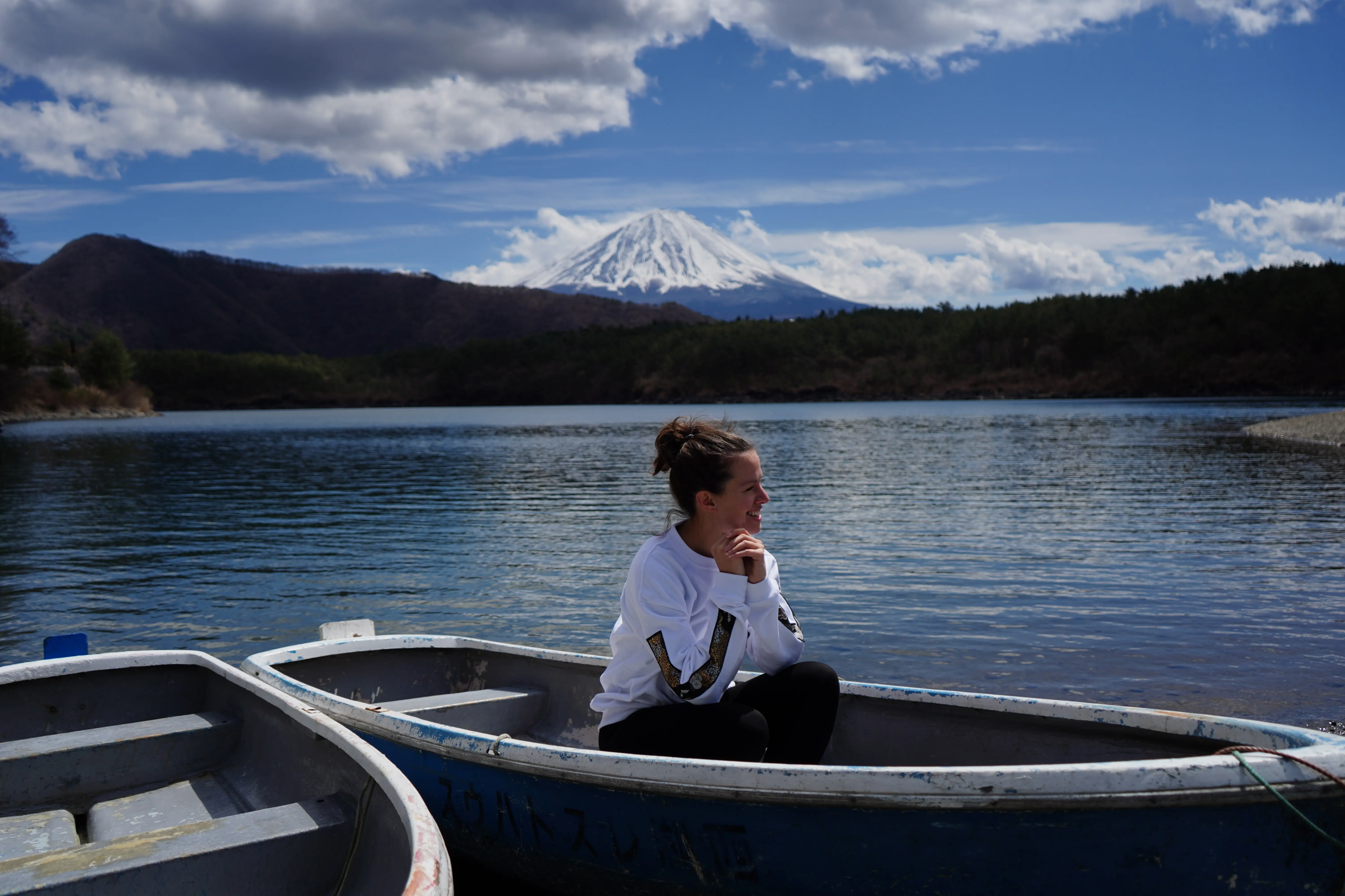 Mount Fuji across a still lake, rowing boats in the foreground